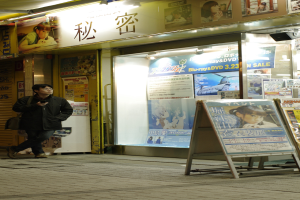 Ein Mann hält ein Mobiltelefon, trägt eine Tasche und hat Schilder mit Text, Geschäfte, Lichter und Papiere mit Text im Hintergrund.