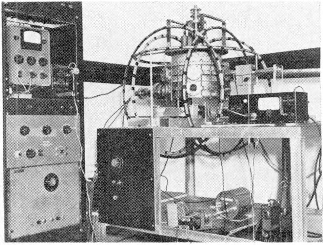 Black and white photo of an electron accelerator machine in a room with a wall in the background and text at the bottom.