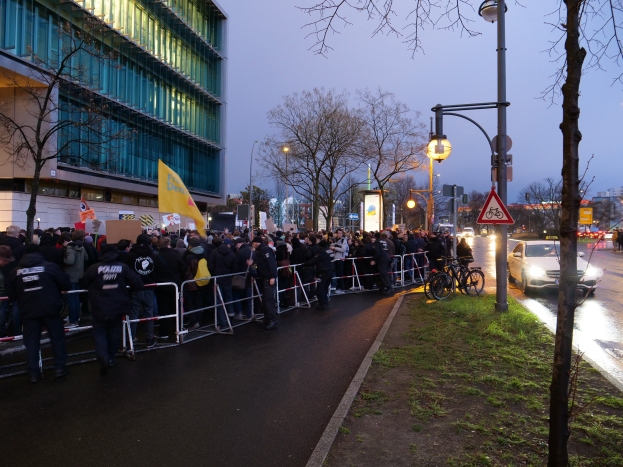 Große Menschenmenge protestiert vor einem Gebäude mit Barrikaden und Schildern in Berlin.