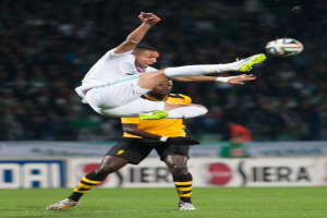 Zwei Männer beim Fußballspielen mit einem Banner im Hintergrund.