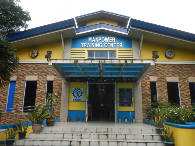 Exterior view of the Manpower Training Center in Manila, Philippines, featuring steps, potted plants, a tree, windows, doors, and signage.