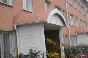 Ein Gebäude mit angeschlossenen Rohren, umgeben von ein paar Pflanzen und Fahrrädern.