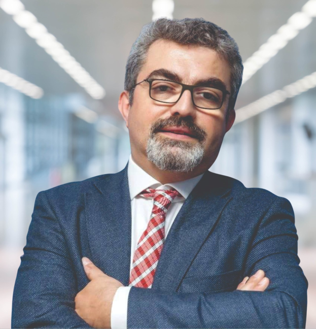 Ein professioneller Mann im Anzug und mit Krawatte, der die Arme verschränkt und eine Brille trägt, vor einem unscharfen Hintergrund, als neuer Marketingchef bezeichnet.