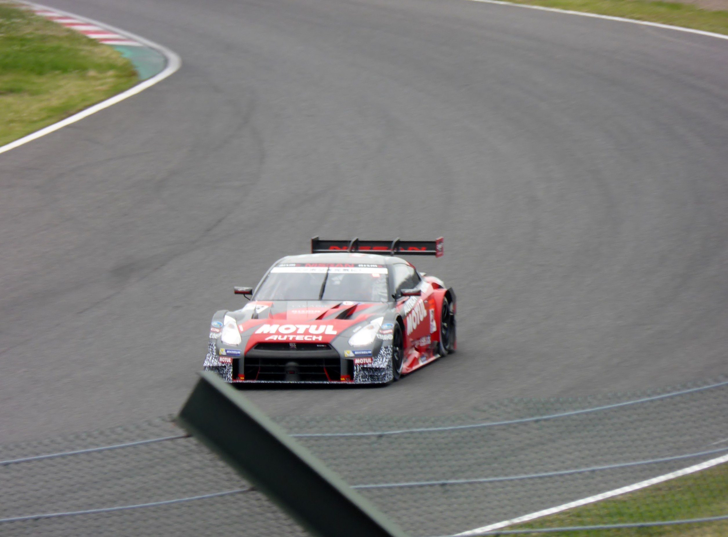 Ein Nissan GT-R Nismo GT3-Rennwagen auf der Nürburgring 24 Stunden-Strecke, mit grünem Gras auf beiden Seiten.