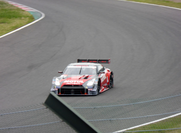 Ein Nissan GT-R Nismo GT3-Rennwagen auf der Nürburgring 24 Stunden-Strecke, mit grünem Gras auf beiden Seiten.