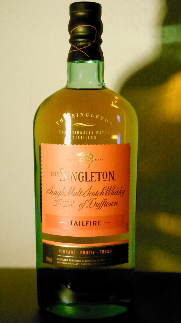 Eine tiefe Bernsteinflasche Singleton of Dufftown Tailfire Single Malt Scotch Whisky mit einem schwarzen Etikett, das ein Löwen- und Schlosswappen zeigt.