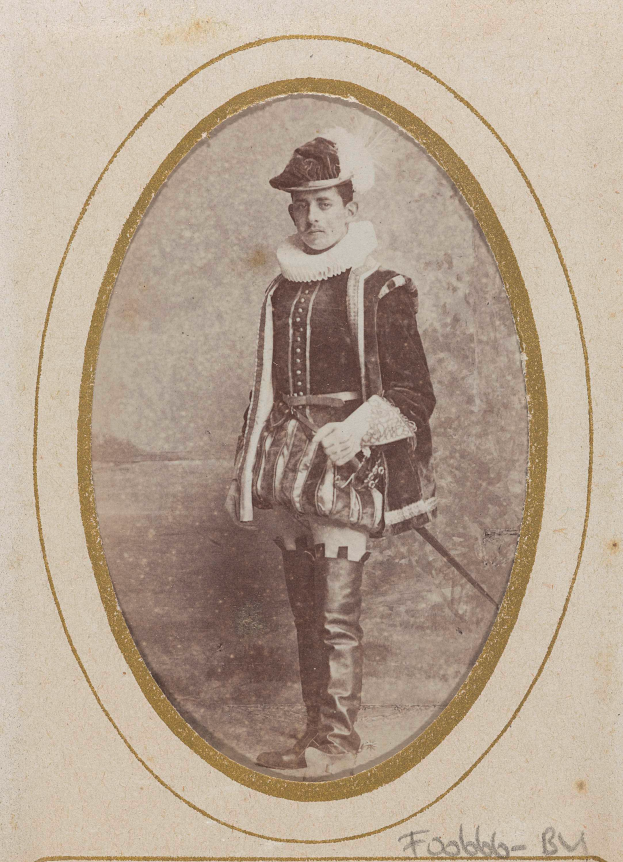 Ein altes Foto eines Mannes in traditioneller schottischer Kleidung, einschließlich Kilt, weißem Hemd, schwarzer Weste und schwarzem Hut, der entschlossen eine Waffe hält.
