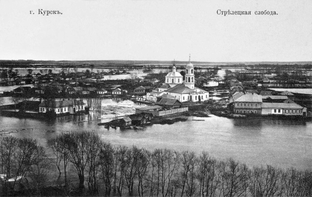 Schwarz-weiß-Fotografie von Krasnoyarsk, Russland, aufgenommen 1892, zeigt einen Fluss, der durch die Stadt fließt, umgeben von Bäumen und Gebäuden.