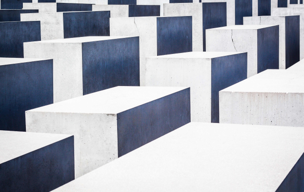 Aerial view of the Holocaust Memorial to the Murdered Jews of Europe in Berlin, featuring numerous rectangular concrete slabs arranged in a grid pattern.