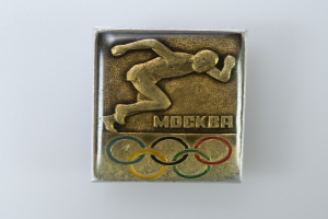Goldmedaille mit Abbildung eines Läufers, Olympischen Ringen und Text auf weißem Hintergrund.