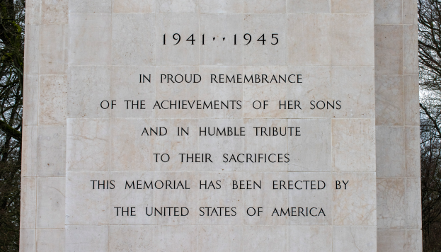 Ein Denkmal mit einer Tafel, auf der "In stolzem Gedenken an die Leistungen ihrer Söhne und in bescheidener Ehrung ihres Opfers" steht, vor einem Hintergrund aus Bäumen und einem klaren blauen Himmel.