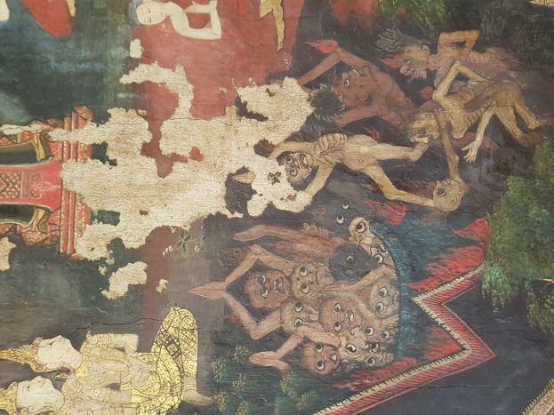 Ein lebendiges Wandgemälde auf einer thailändischen buddhistischen Tempelwand zeigt Menschen und Tiere im traditionellen thailändischen Stil, darunter ein Löwe, eine Giraffe, ein Affe und ein Zebra, vor einer üppigen grünen Landschaft mit Bäumen und Bergen.