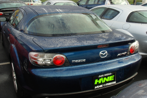 Mehrere Autos stehen auf einem Parkplatz mit einem Schild, auf dem unten Text zu sehen ist.