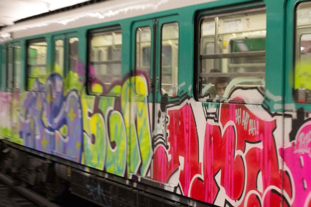 Ein Zug auf den Schienen mit zwei Personen darin und Graffiti an seiner Außenseite.