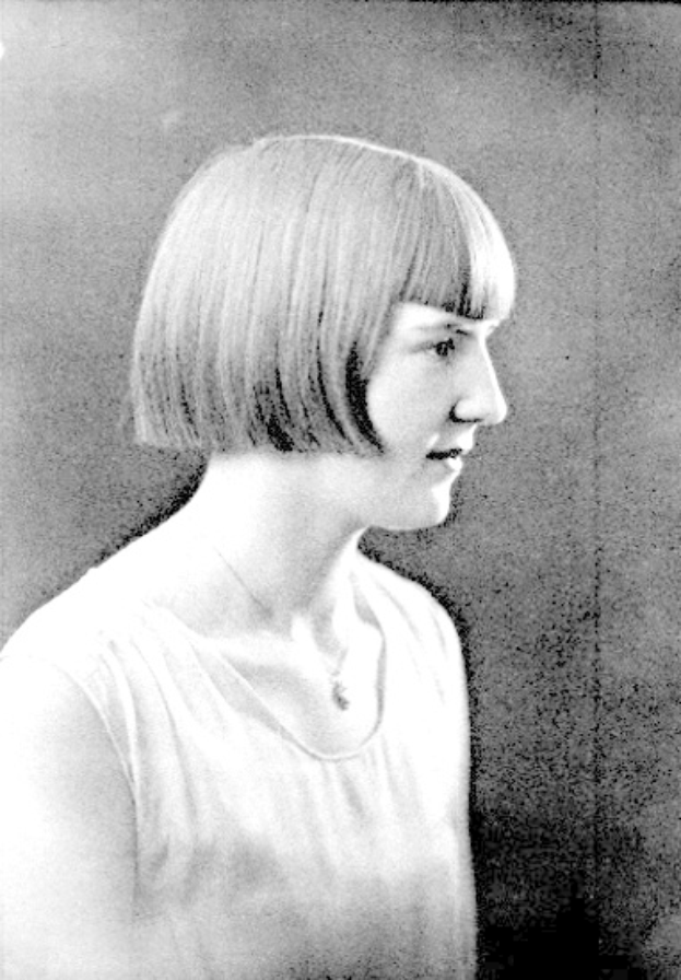 Ein Schwarz-Weiß-Foto einer Frau mit einem kurzen Bob-Haarschnitt, ihr Gesicht ist deutlich zu sehen, mit zur Seite blickenden Augen und leicht geöffneten Lippen.