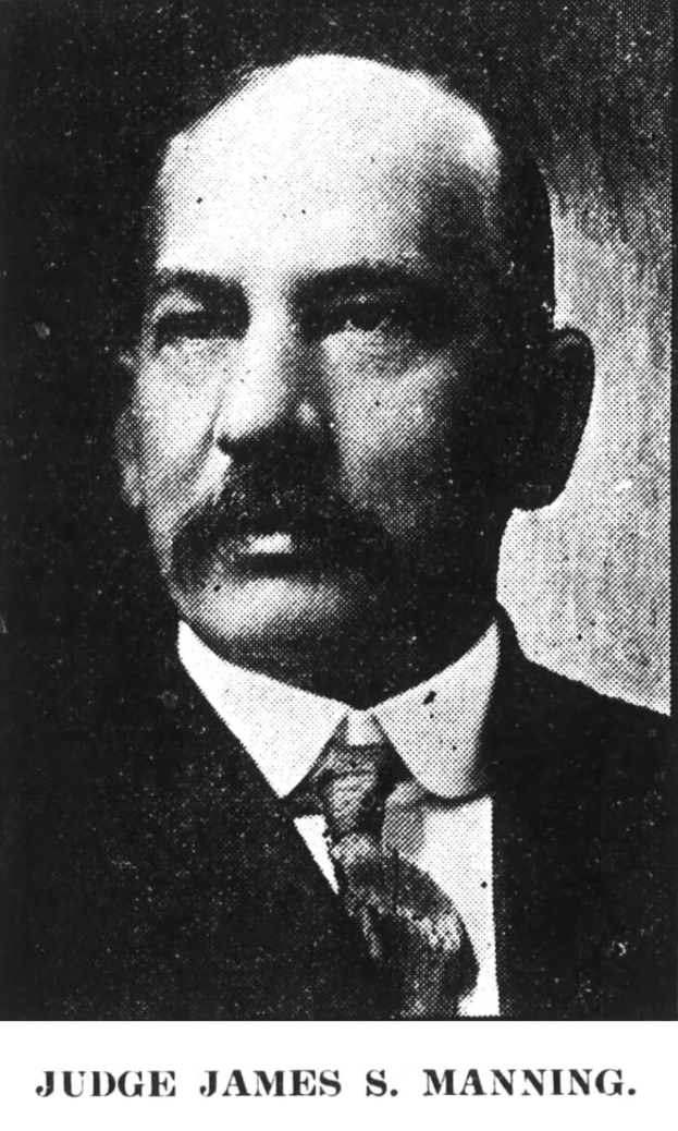 A suited man testifies at a Senate Judiciary Committee hearing, seated at a table with a nameplate, microphone, and water bottle, facing a wall.