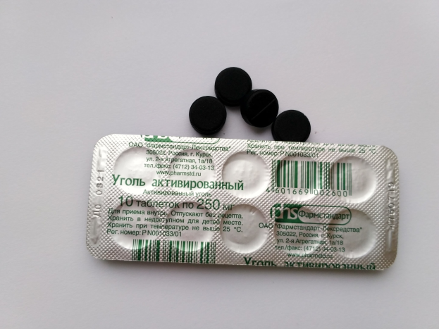 Ein weißer Tisch mit einer Blisterpackung schwarzer Pillen, mit Text und einem Barcode.