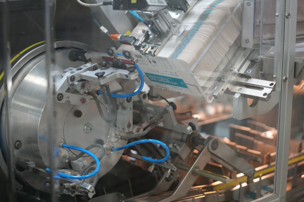 Automatisierte Verpackungsmaschine auf einem Fabriktisch mit unscharfen Hintergrundobjekten.