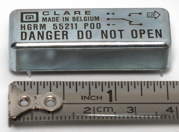 Metallbox mit der Aufschrift "Danger Do Not Open" neben einer Lineal auf einer weißen Oberfläche.