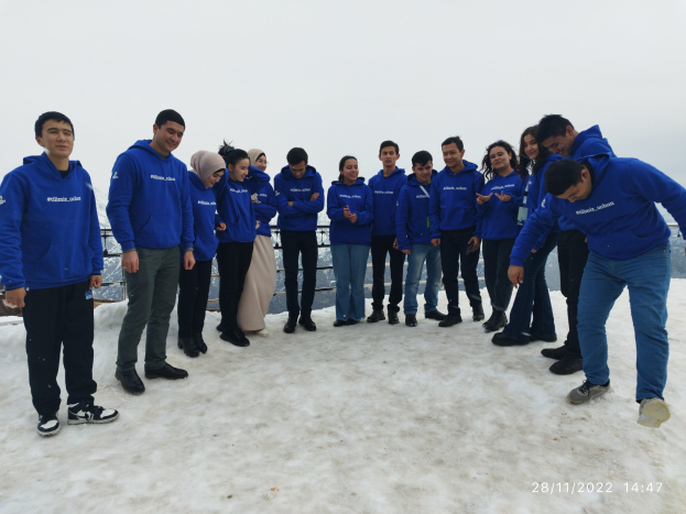 Gruppe von Menschen auf einem schneebedeckten Hügel mit einem Geländer im Hintergrund und klarem Himmel, die an einem Wintertrainingsprogramm in der Türkei teilnehmen.
