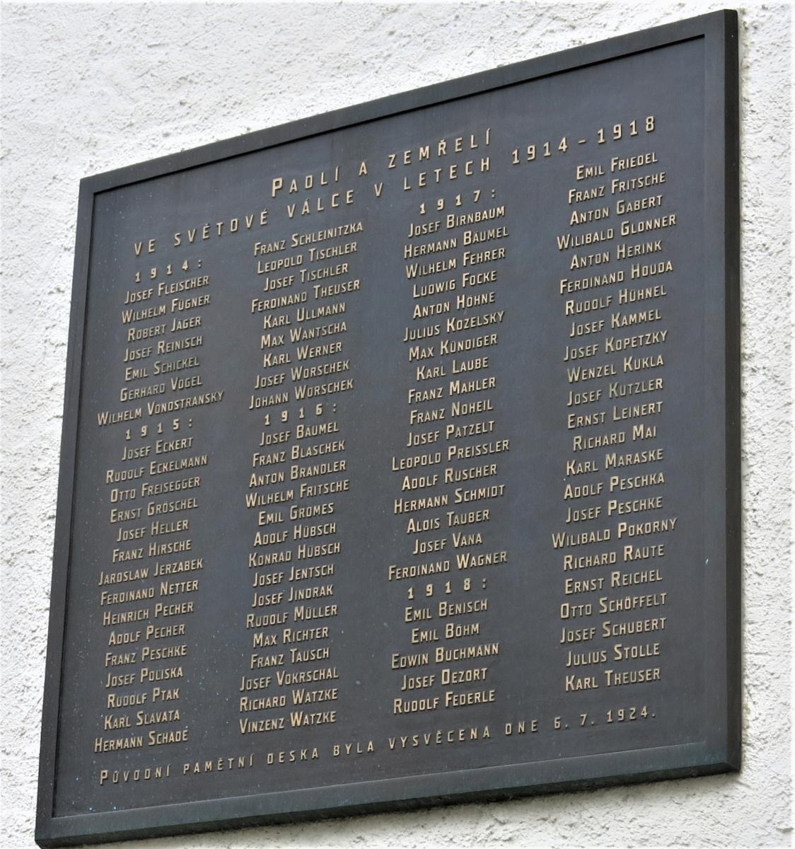 Plaque mounted on a building wall with the inscription "Plaque for the victims of the Holocaust" in a dark material with a decorative border.
