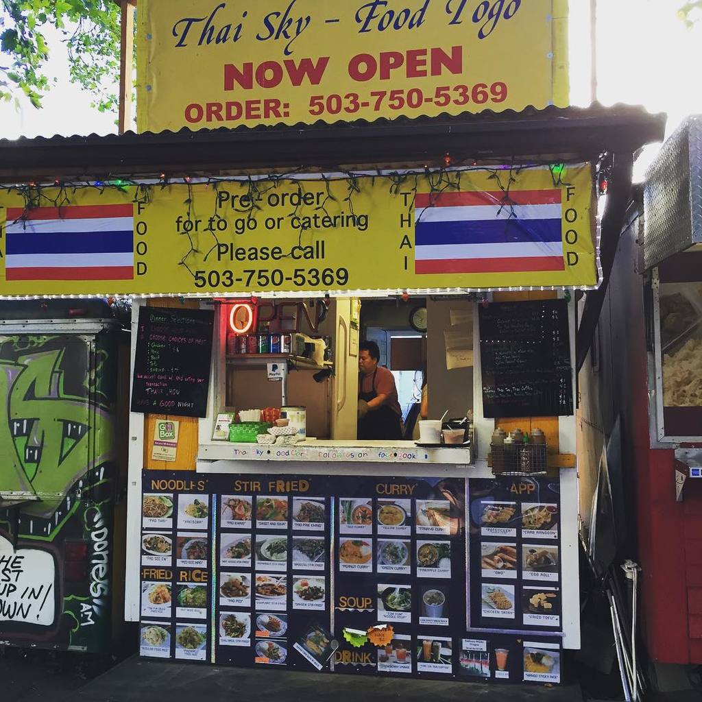 Ein Schaufenster mit verschiedenen Gegenst├Ąnden, darunter Get├Ąnkedosen, Speisekarten, eine Uhr, Gew├╝rze in Plastikbeh├Ąltern, Gew├╝rze, Werbetafeln und Namensschilder, unter einem Himmel.