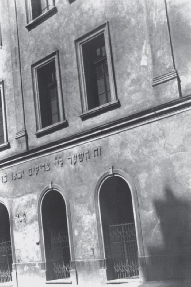 Schwarz-weiß-Foto eines Gebäudes in Jerusalem mit Fenstern, Türen und einem Metallzaun, das mutmaßlich eine jüdische Synagoge ist.