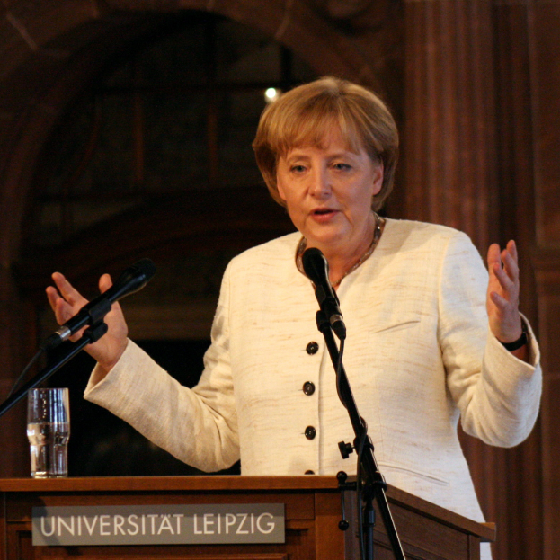 Bundeskanzlerin Angela Merkel steht an einem Rednerpult mit einem Mikrofon und einem Glas Wasser und hält eine Rede an der Universität Leipzig.