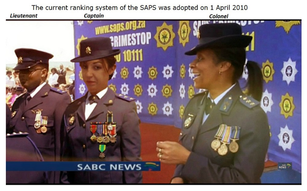 Gruppe von Menschen in Uniformen und Hüten mit einem Banner, das Text an der Ober- und Unterseite trägt, der besagt "Das aktuelle Rankingsystem der SAP wurde am 1. April 2010 übernommen."