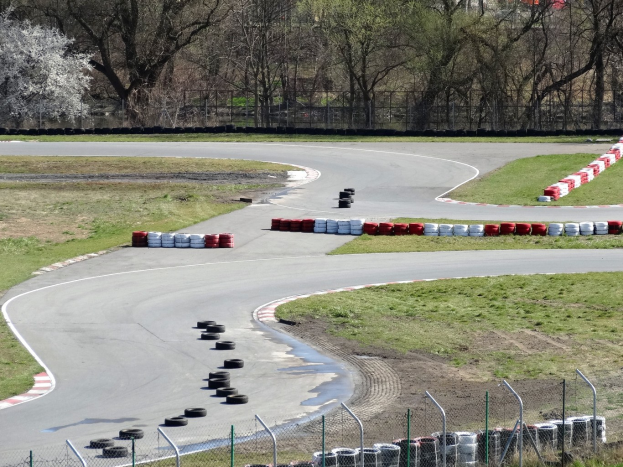 Rennstrecke voller Reifen, gesäumt von Gras und Maschendrahtzaun, mit Bäumen im Hintergrund