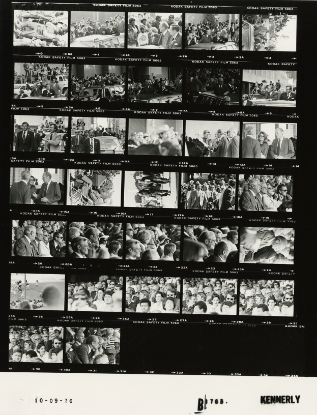 Schwarzes und weißes Foto einer vielseitigen Menge, die lächelt und auf einen Fernseher schaut, mit Text unten.