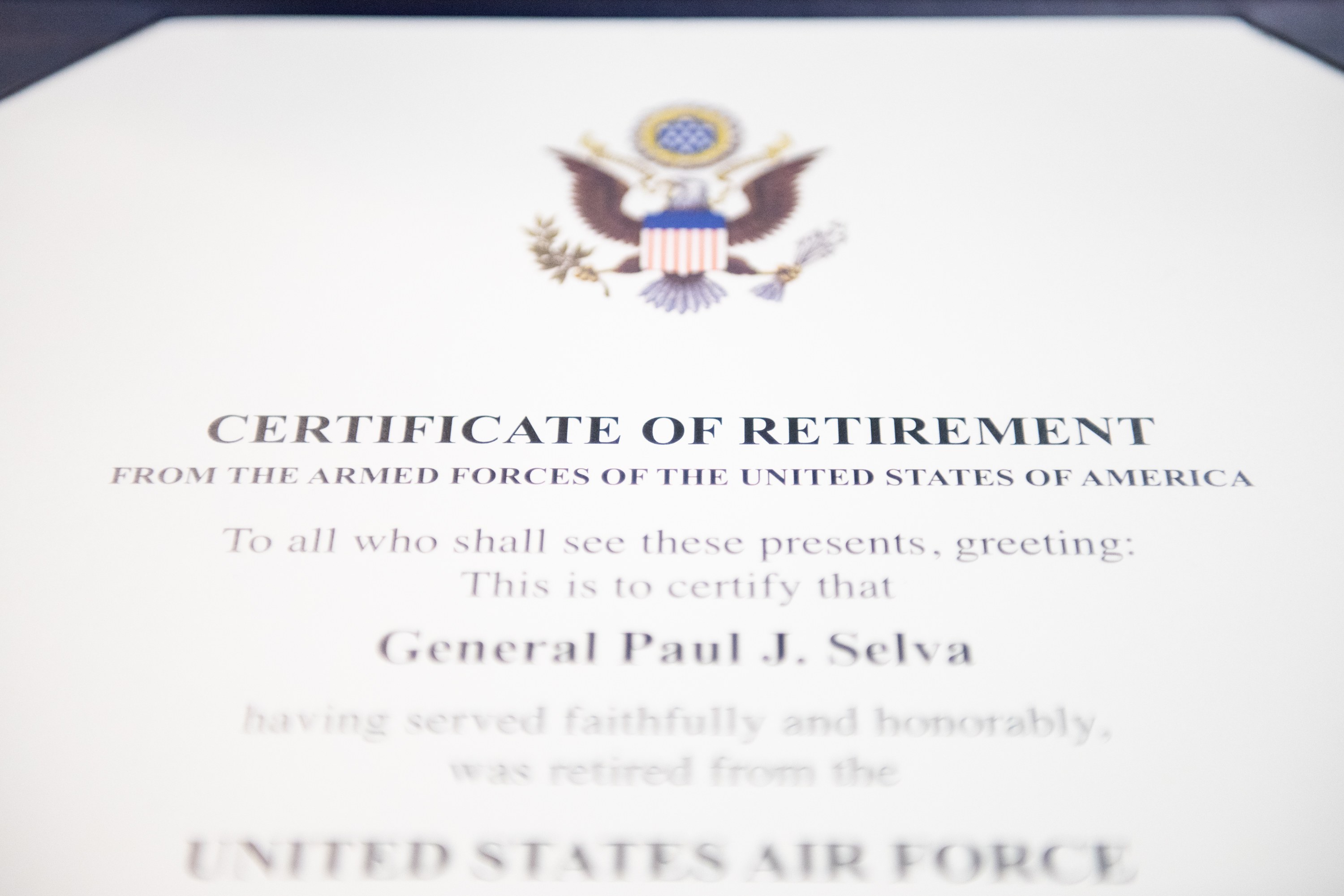 Rahmenurkunde für den Ruhestand von der United States Air Force mit blauem Rand, schwarzer Schrift und einem zentralen Schild-Logo mit einem Stern, einem Lorbeerkranz und einer Banneraufschrift "Ruhestand".