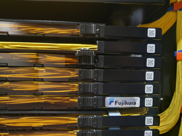 Ein Close-up eines Server-Racks in einem Rechenzentrum, mit elektronischen Geräten und Kabeln, die damit verbunden sind und ein Netzwerk bilden.