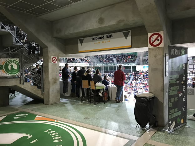 Eine Gruppe von Menschen steht vor einem sitzenden Publikum in einem Stadion während eines Ereignisses mit Schildern, die "Boston Celtics vs New York Jets" anzeigen.
