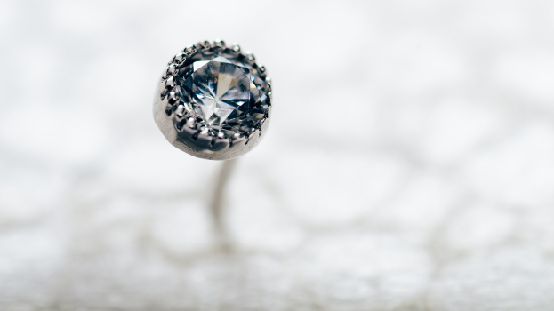 Nahaufnahme eines Diamanten auf einer weißen Oberfläche mit unscharfem Hintergrund.