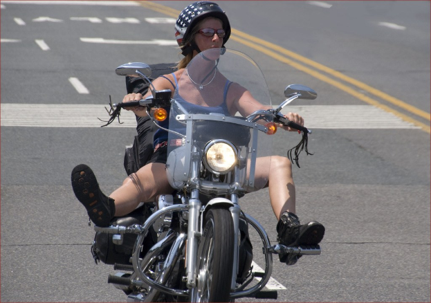 Eine Frau fährt mit dem Fahrrad auf der Straße und trägt einen schwarzen Helm.