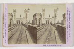 Schwarz-weiß-Stereoskopiebild einer Eisenbahnschiene mit der Eisenbahnbrücke in Köln, Deutschland, das Eisenbahnschienen, Wände, Stäbe, Statuen, Himmel und Text zeigt.