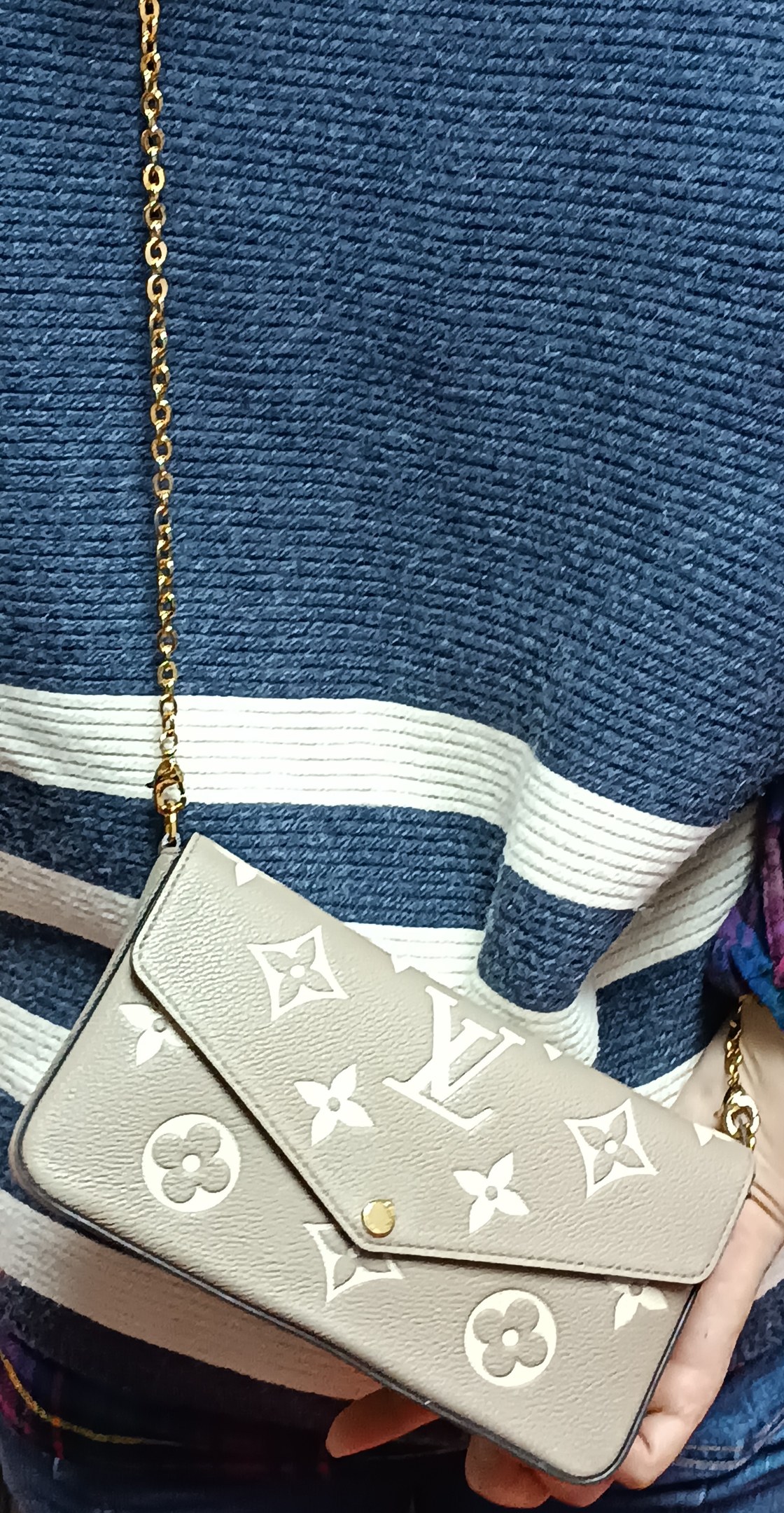 Eine Person In Einem Blauen Und Weißen Kleid, Die Eine Louis Vuitton Monogram Canvas Pochette Accessoires MM Tasche Mit Einer Goldkette Hält.
