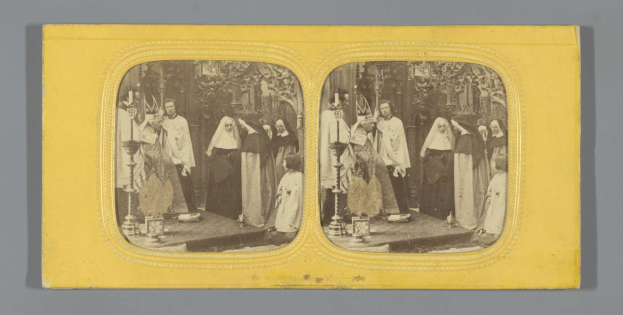 Ein Schwarz-Weiß-Foto einer Gruppe von Menschen in traditioneller russischer Kleidung, die auf einer Bühne mit grauem Hintergrund lächeln.