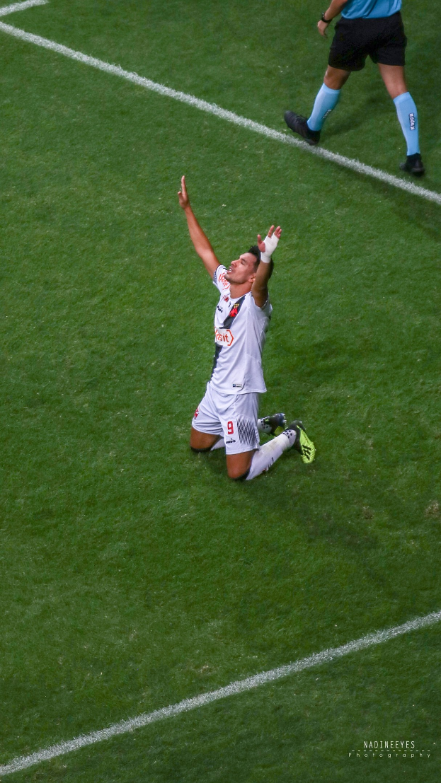 Ein Fußballspieler in Uniform kniet auf dem Boden mit ausgestreckten Armen in Feierstellung.