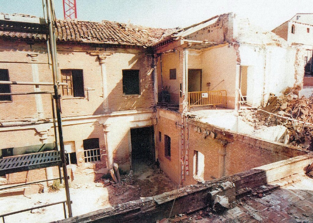 Ein teilweise abgerissenes Gebäude mit einer Barriere, sichtbaren Fenstern und etwas, das wie eine Leiter aussieht.