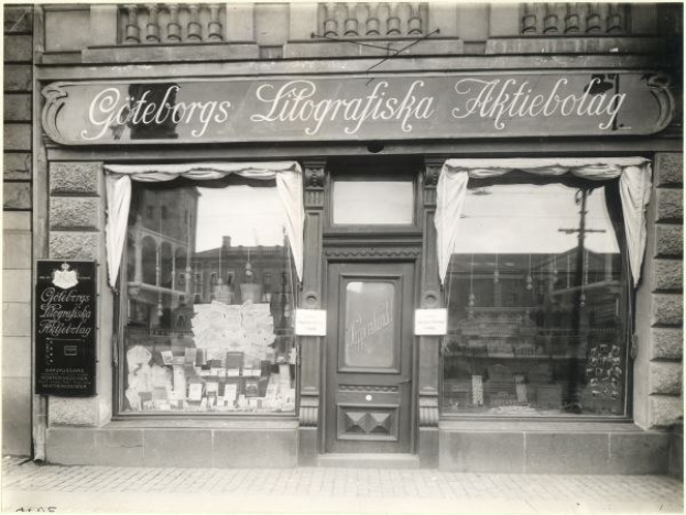 Schwarzes und weißes Foto einer Geschäftsfront in Stockholm, Schweden, mit einer Tür, Fenstern, Vorhängen und einer Tafel mit der Aufschrift "Göteborgs Litografiska Aktiebolag."