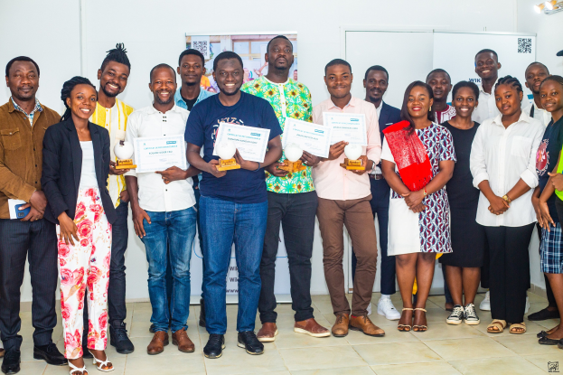 Gruppe von Menschen, die strahlen und Zertifikate in einem Raum mit einem Tisch, Tafeln und einem Plakat im Hintergrund halten, feiert die Gewinner des 2019 WIK Awards.